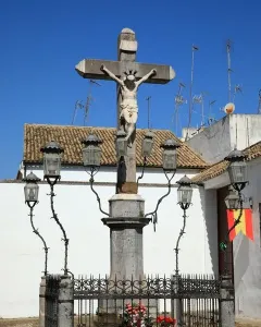 Christ of the Lanterns crucifix in Córdoba, illuminated by ornate black lanterns and surrounded by a decorative iron fence.