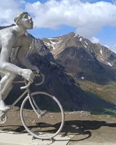 Géant du Tourmalet statue of a naked cyclist on a bicycle beside two cyclists and a Tourmalet sign