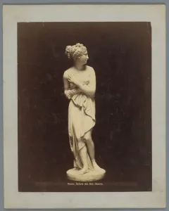 Sepia photograph of the Venus Italica marble statue, shown full-length against a dark background.