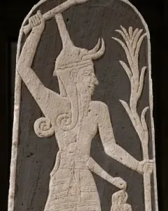 Stele of Baal with a horned deity raising a thunderbolt and holding a spear, with a smaller figure beside him.