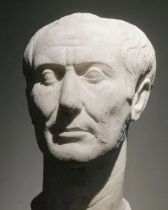 Weathered marble bust of the Tusculum portrait showing a stern-faced man with receding wavy hair and deep facial wrinkles.