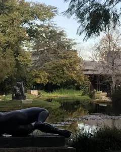 The River, a dark reclining nude female sculpture on a stone plinth outdoors.