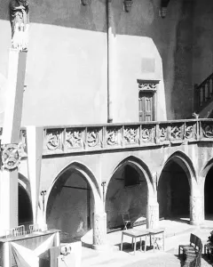 Copernicus Monument in a gothic courtyard, showing a robed statue holding a spherical instrument on a decorated pedestal.