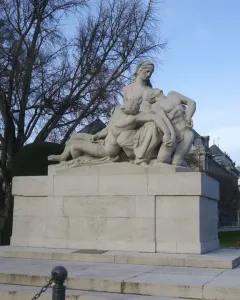 Stone war memorial with a central female figure cradling two other figures on a tiered base with inscriptions.