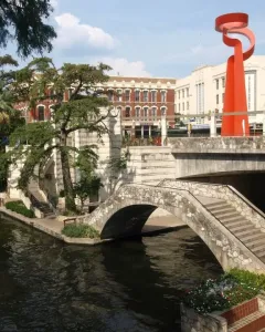 La Antorcha de la Amistad rising above a stone bridge in downtown San Antonio.