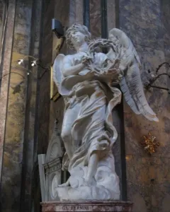 Bernini\'s Angel with the Crown of Thorns, a white marble angel holding a thorny wreath and looking upward.
