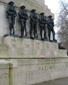 Guards Memorial with five dark soldier figures standing on a stone pedestal with engraved dedication text below.