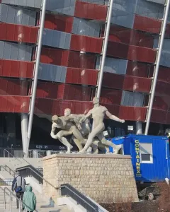 Sztafeta sculpture showing three male figures in dynamic running poses on a stone pedestal.