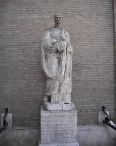 Abbot Luigi, a weathered stone statue of a robed male figure on an inscribed plinth.