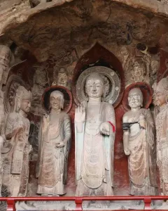 Ancient rock carvings at Huangze Monastery, including a large central haloed statue surrounded by smaller figures in a cave-like recess.