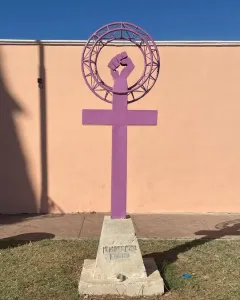 Antimonumenta sculpture in purple, shaped like the Venus symbol with an upright fist on a concrete base.