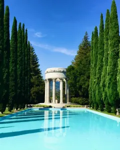 Pulgas Water Temple reflected in a still reflecting pool, with a lone person standing nearby.