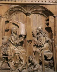 Wooden relief of Saint Luke seated beside the Madonna in an ornate architectural alcove.