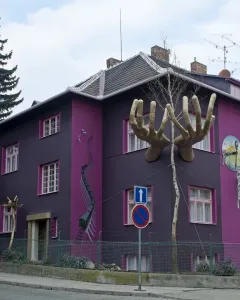Kristek House in Brno with a dark purple facade, pink window accents, and surreal sculptural elements including large hands and a melting clock.