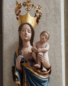 Inkpot Madonna statue of a crowned woman holding a child, with an inkpot and quill, mounted on a decorative bracket.