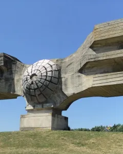 Monument to the Revolution of the People of Moslavina on a grassy hill, with a central circular concrete form and broad abstract wings.