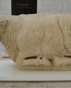 Bull of Osuna stone sculpture shown in profile on a white plinth.