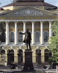 Pushkin statue stands before the Mikhailovsky Palace with a classical facade and trees in the background.