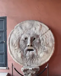 Bocca della Verità stone mask with a bearded face and open mouth on a pedestal