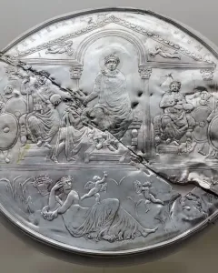 Disc of Theodosius showing a damaged silver relief with an enthroned figure, attendants, and a reclining female figure among wheat stalks.