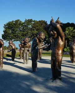 A-maze-ing Laughter sculptures of bald men with laughing expressions in a waterfront park.
