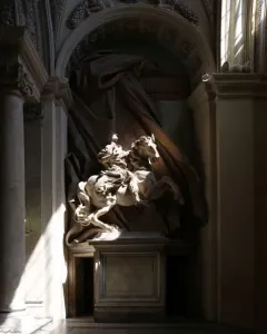 The Vision of Constantine, a white marble equestrian statue lit by sunlight inside an ornate niche.
