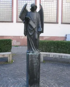 Frankfurter Engel sculpture showing a winged figure in flowing robes holding a scroll and a small book or box.