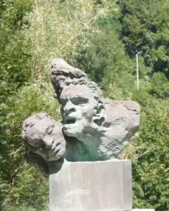 War Memorial of Capoulet-et-Junac with a weathered stone cluster of anguished faces on a concrete pedestal.