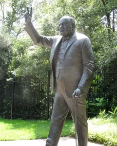 Winston Churchill statue making a V-for-Victory sign with one hand and holding a cane.