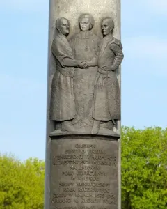 Electio Viritim Monument in Warsaw with a bronze plaque below a relief of three historical figures.