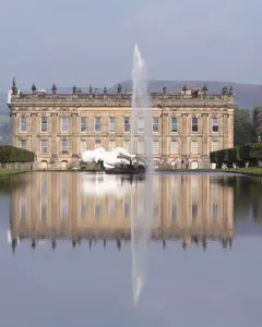 Emperor Fountain rising from a reflecting pool in front of a grand historic mansion