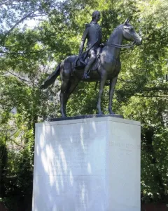 Bernardo de Gálvez equestrian statue on a tall stone pedestal surrounded by trees.
