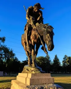 End of the Trail bronze sculpture showing a slumped rider on a lowered horse atop a stone base.