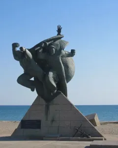 Monument of Eupatoria Assault bronze sculpture with three figures on a stone base by the sea.