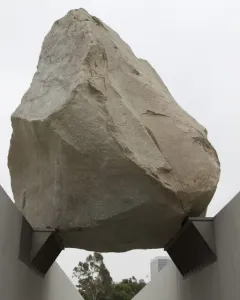 Levitated Mass shows a massive boulder suspended above a concrete pathway between sloping walls.