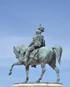 Victor Emmanuel II equestrian statue in bronze atop a stone pedestal against a blue sky.