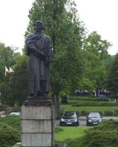Mickiewicz Monument, a dark statue of a bearded man holding a book on a tall stone pedestal in a park.