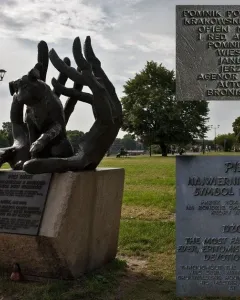 Bronze Monument to Dog Jock sculpture showing a dog nestled between two large hands on a stone pedestal in a park.