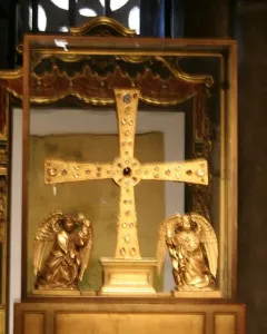 The Cross of the Angels, a jeweled golden cross displayed in a glass case with kneeling angel figures beside it.
