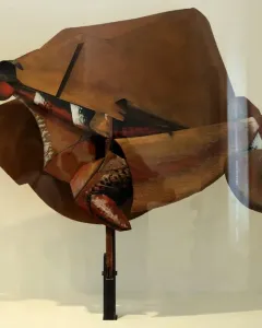 Dynamism of a Speeding Horse + Houses sculpture with angular brown, red, black, and white planes on a dark stand.