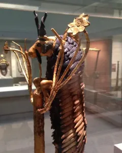 Ram in a Thicket sculpture showing a golden ram standing on hind legs with dark horns and a stylized golden thicket.