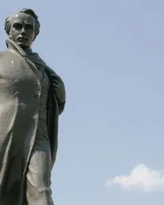 Taras Shevchenko Memorial bronze statue of a man in a long coat against a blue sky