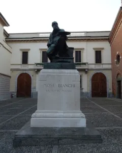 Monument to Mosè Bianchi showing a bronze seated statue of the bearded artist holding a palette on a stone pedestal.
