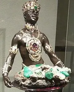 Moor with Emerald Plate statue holding a tray with green crystals, wearing a jeweled crown and ornate gold jewelry.
