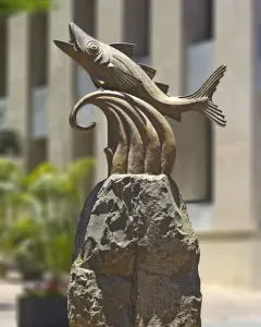 The Chicharro Sculpture showing a metallic fish leaping from a rugged rock pedestal.