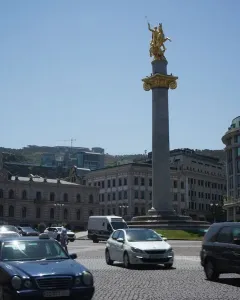The Freedom Monument with a golden equestrian statue atop a tall column in a city square.