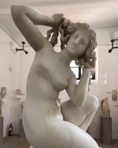 Crouching Venus, a white marble statue of a nude woman crouching with her hands raised to her hair.