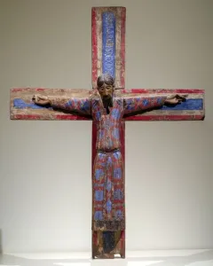Batlló Majesty wooden crucifix showing Christ in a patterned red and blue tunic with outstretched arms.