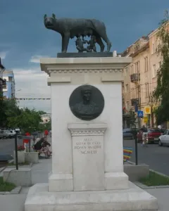 Capitoline Wolf sculpture of a she-wolf suckling two infants on a tall stone pedestal.