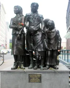 Trains to Life – Trains to Death monument showing several bronze children on a stone base with a plaque.